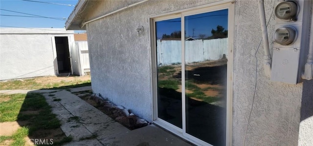 view of side of home with fence and stucco siding