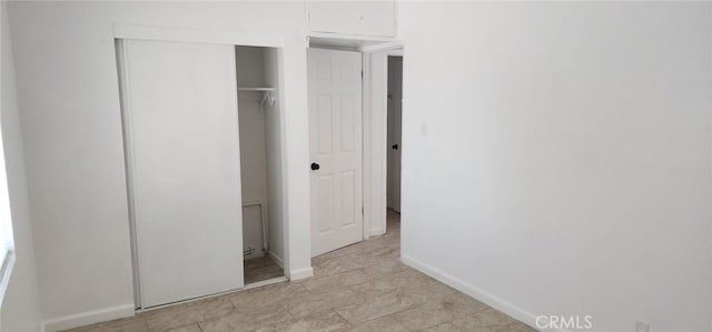 unfurnished bedroom with a closet and baseboards