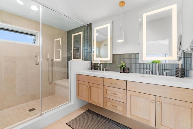 bathroom featuring a shower stall, tasteful backsplash, double vanity, and tile patterned floors