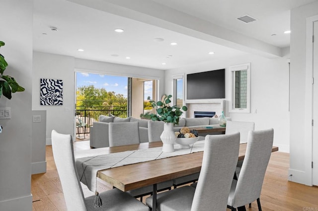 dining space featuring light wood-type flooring, recessed lighting, baseboards, and a fireplace
