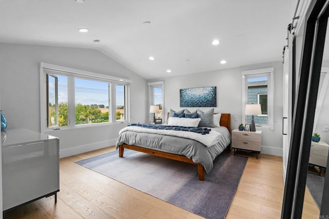 bedroom featuring lofted ceiling, light wood finished floors, recessed lighting, baseboards, and a barn door
