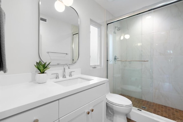 bathroom featuring toilet, a shower stall, and vanity