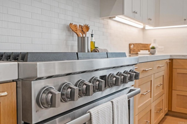 kitchen view of stainless steel range, backsplash, and light countertops