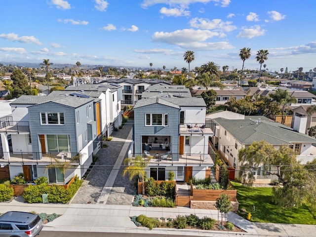view of front facade featuring a residential view, a balcony, driveway, and fence
