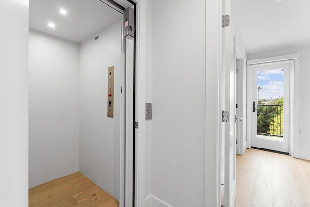hall with elevator, light wood finished floors, and recessed lighting