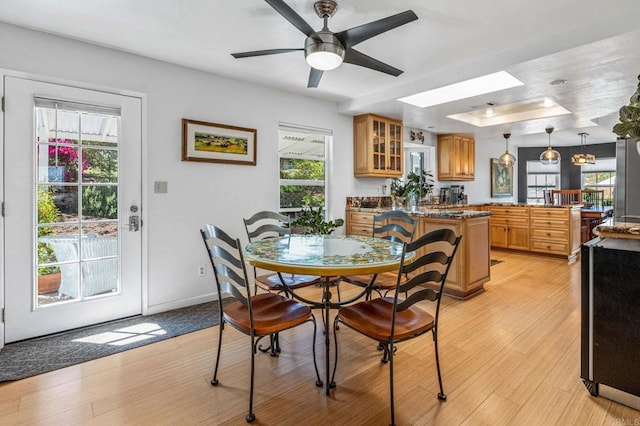 dining room with a skylight, a healthy amount of sunlight, and light wood finished floors