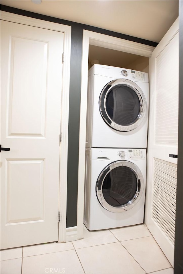 laundry room with tile patterned floors, stacked washer and clothes dryer, and laundry area