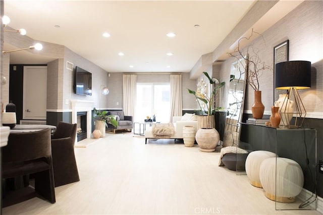 living room featuring recessed lighting, wood finished floors, and a fireplace with raised hearth