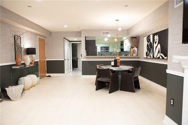 dining area with wainscoting, baseboards, visible vents, and light wood finished floors