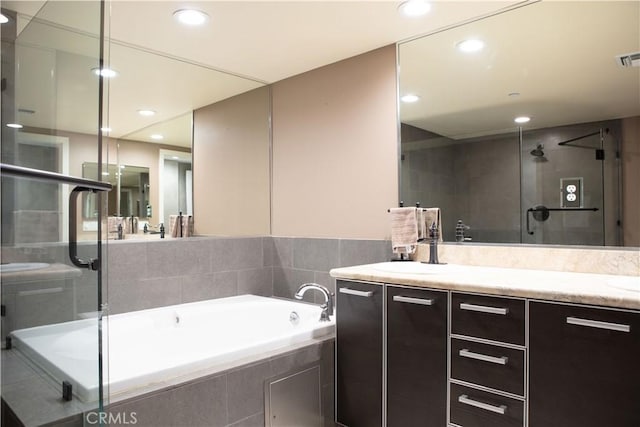bathroom featuring a sink, a stall shower, a bath, double vanity, and recessed lighting
