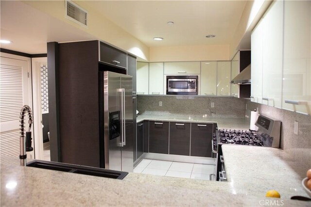 kitchen with visible vents, wall chimney range hood, light tile patterned flooring, tasteful backsplash, and appliances with stainless steel finishes