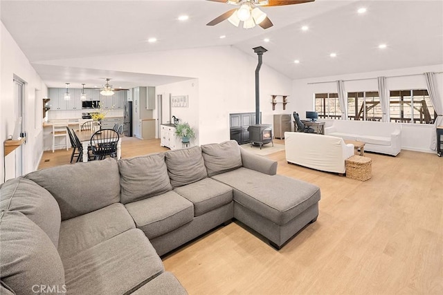 living area featuring a wood stove, recessed lighting, light wood-style floors, high vaulted ceiling, and a ceiling fan