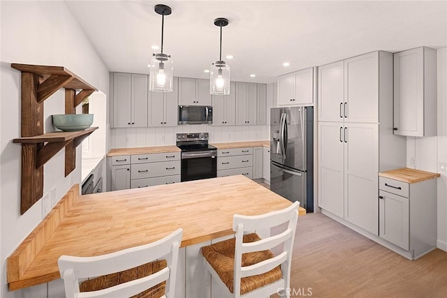 kitchen with recessed lighting, gray cabinets, light wood-style flooring, wooden counters, and appliances with stainless steel finishes