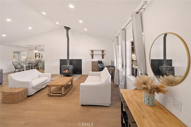 living area featuring a wood stove, recessed lighting, high vaulted ceiling, and a ceiling fan