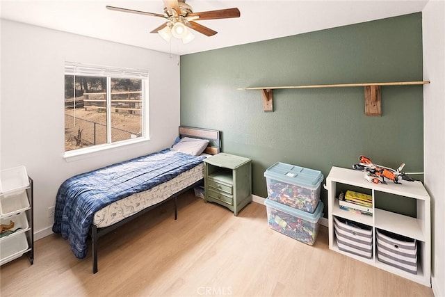 bedroom with baseboards, wood finished floors, and ceiling fan