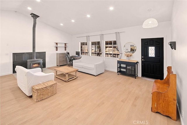 living room with a wood stove, light wood-style floors, baseboards, recessed lighting, and high vaulted ceiling