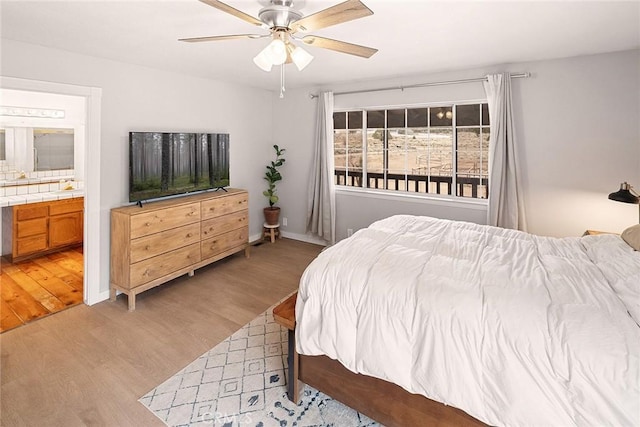 bedroom featuring ensuite bathroom, ceiling fan, and light wood finished floors