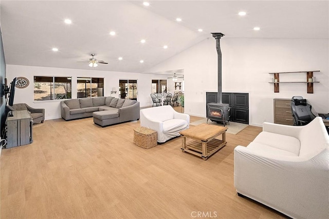 living room featuring a wood stove, baseboards, recessed lighting, light wood finished floors, and a ceiling fan