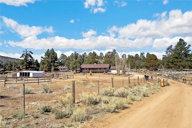 view of yard featuring fence, a rural view, an exterior structure, and an outbuilding
