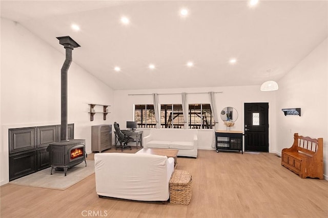 living room featuring light wood-type flooring, recessed lighting, high vaulted ceiling, and a wood stove