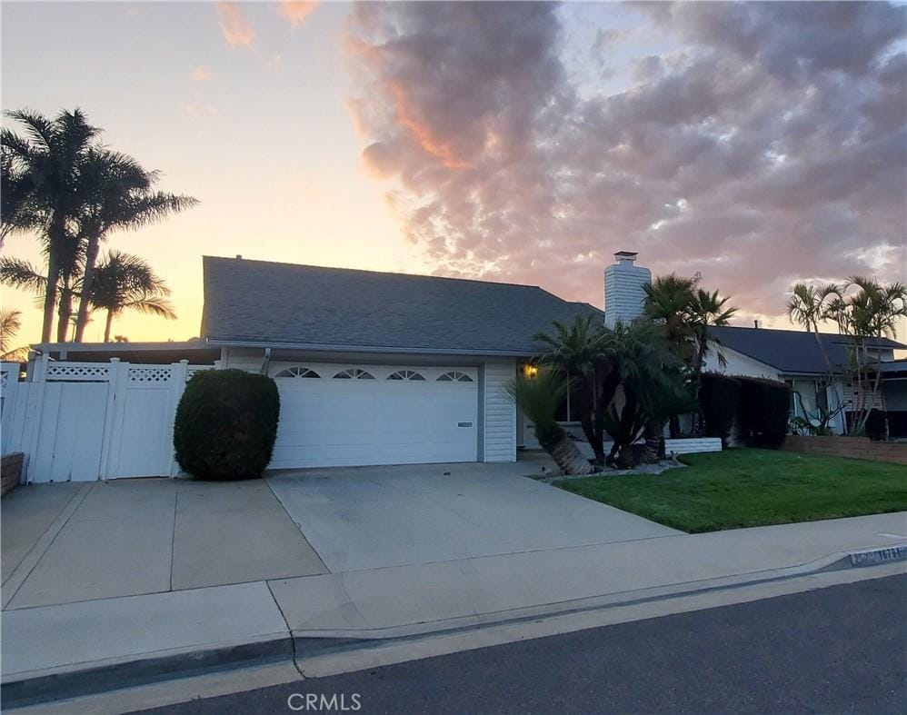 16791 Leafwood Cir, Huntington Beach, CA 92647 - view of front of home featuring a front yard, a chimney, a garage, and concrete driveway