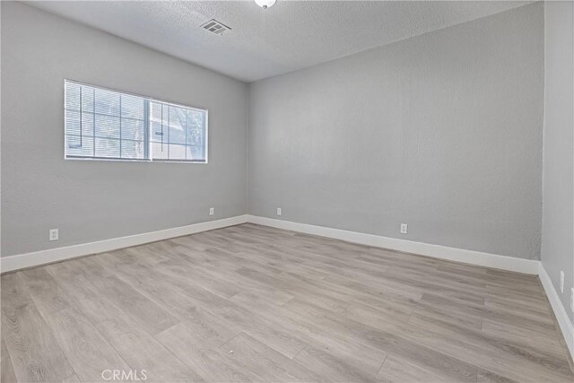 1335 N Lugo Ave, San Bernardino, CA 92404 - spare room with a textured ceiling, visible vents, light wood finished floors, and baseboards