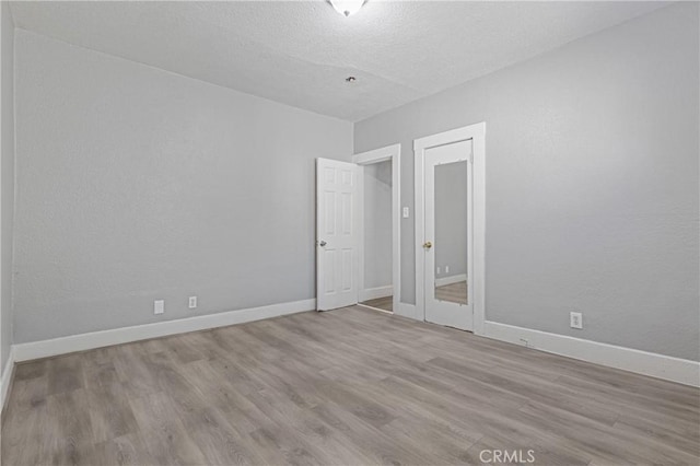 1335 N Lugo Ave, San Bernardino, CA 92404 - spare room featuring a textured ceiling, a textured wall, wood finished floors, and baseboards
