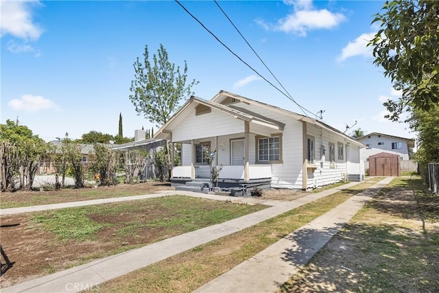 1335 N Lugo Ave, San Bernardino, CA 92404 - shotgun-style home featuring a porch, an outbuilding, a storage shed, driveway, and a front yard