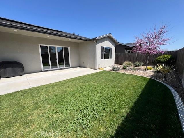 back of property featuring a patio, stucco siding, a fenced backyard, and a lawn