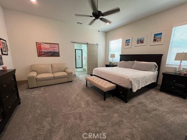 carpeted bedroom with a ceiling fan, visible vents, and a barn door