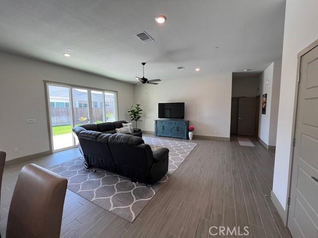 living area featuring visible vents, baseboards, a ceiling fan, recessed lighting, and wood finished floors