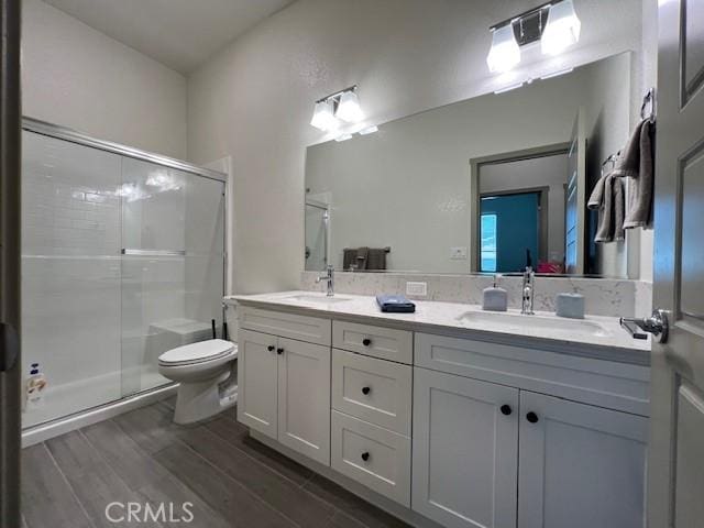 full bathroom with a stall shower, wood finished floors, and a sink