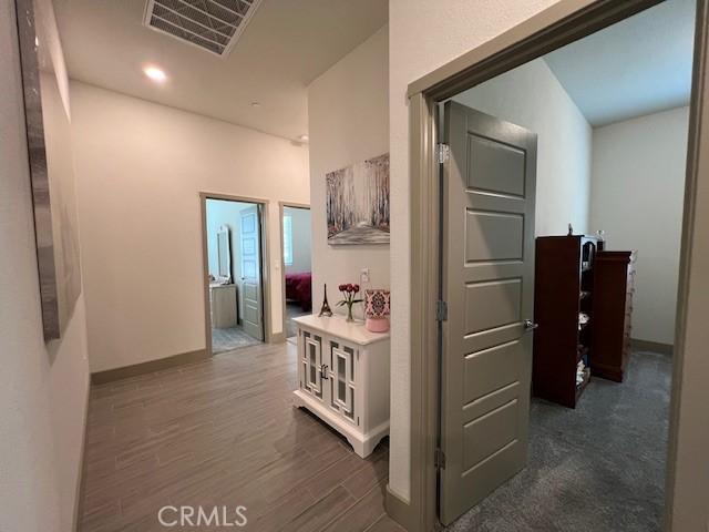 hallway with dark wood-style flooring, baseboards, and visible vents