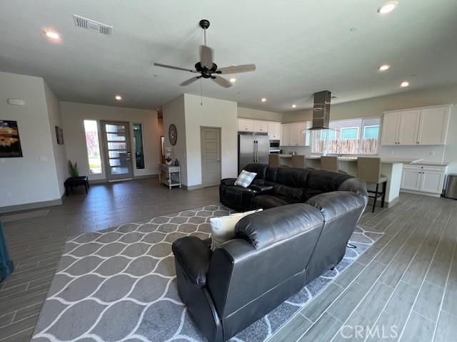 living area with light wood finished floors, visible vents, ceiling fan, and a healthy amount of sunlight
