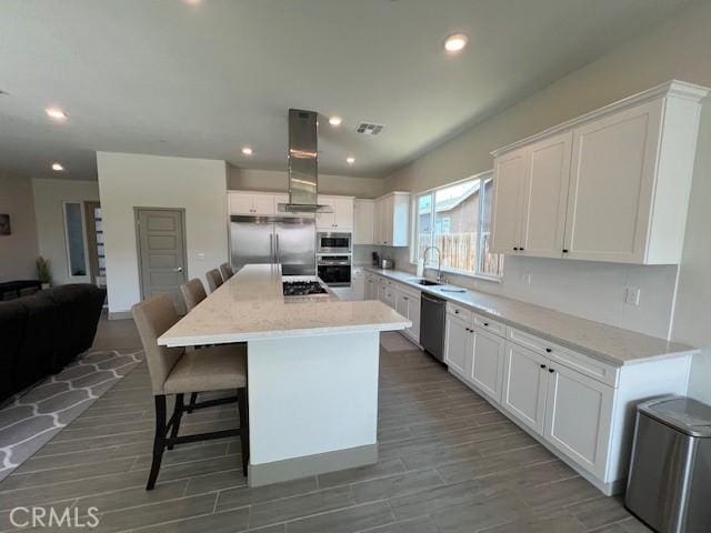 kitchen with a kitchen bar, built in appliances, exhaust hood, and white cabinets