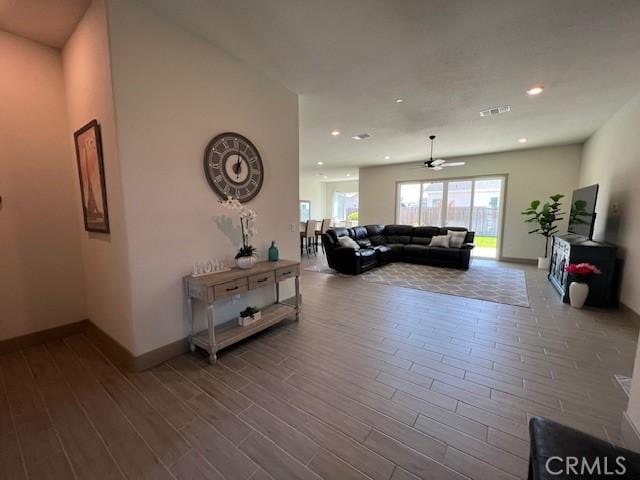 living area featuring visible vents, baseboards, a ceiling fan, and wood finished floors