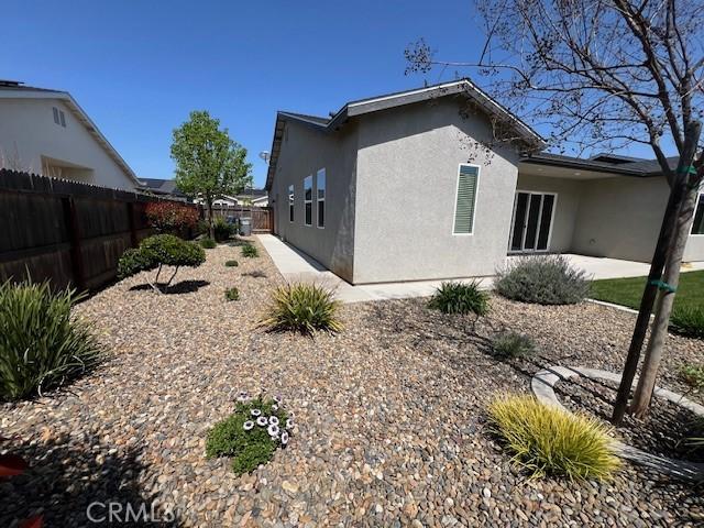 view of side of property featuring a patio, stucco siding, and fence