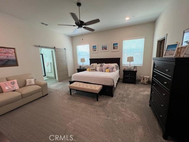 bedroom featuring visible vents, ceiling fan, carpet, and a barn door