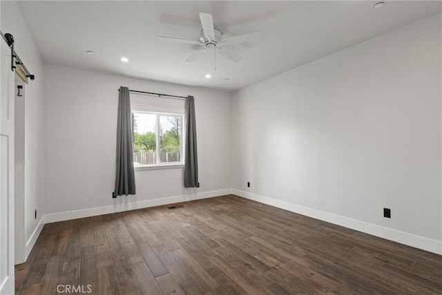 spare room with baseboards, recessed lighting, dark wood-style floors, a barn door, and ceiling fan