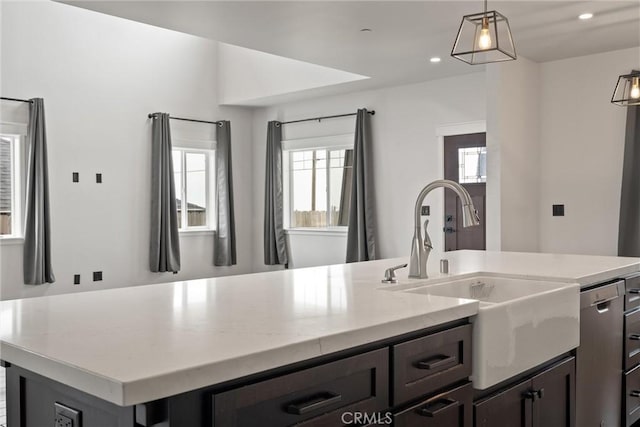 kitchen featuring light stone counters, recessed lighting, a center island with sink, pendant lighting, and a sink