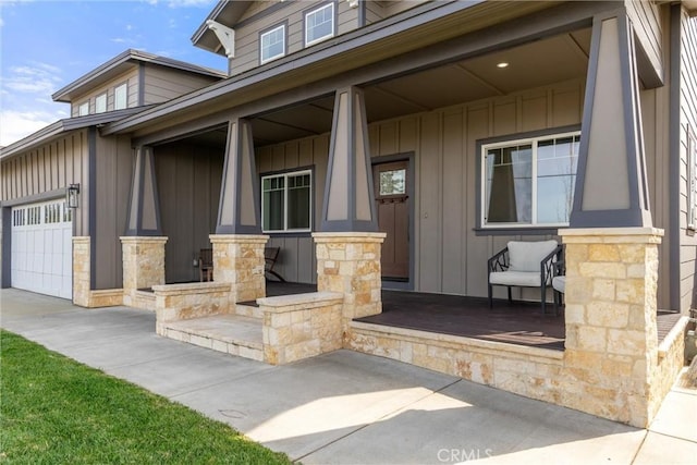 entrance to property featuring board and batten siding, an attached garage, a porch, and stone siding