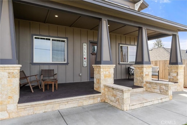 doorway to property with board and batten siding, covered porch, and stone siding