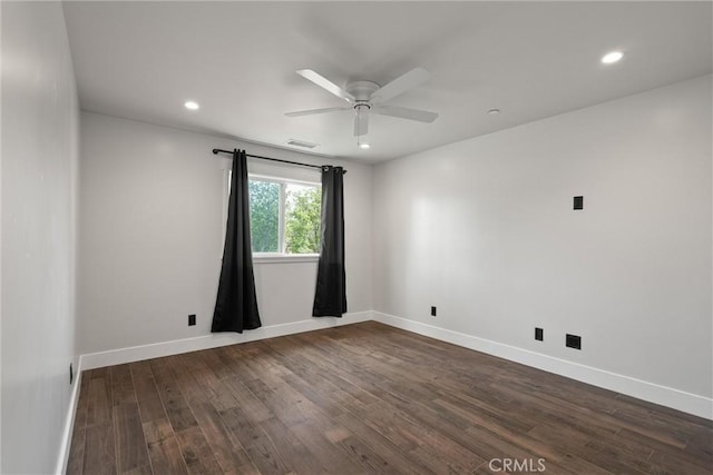 empty room featuring dark wood-style flooring, visible vents, baseboards, and a ceiling fan