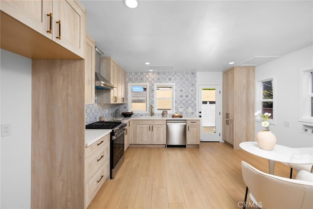 kitchen with light brown cabinets, gas stove, light countertops, stainless steel dishwasher, and a sink