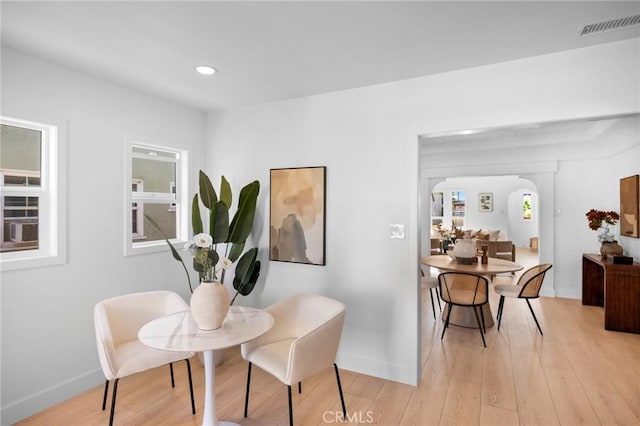 dining room with light wood-style flooring, arched walkways, visible vents, and recessed lighting