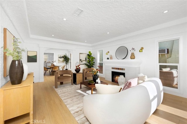 living room featuring light wood finished floors, a lit fireplace, and a textured ceiling