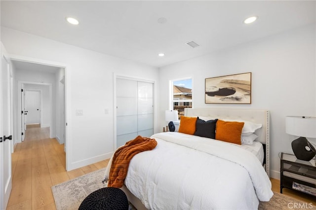 bedroom featuring a closet, recessed lighting, light wood-style floors, and baseboards
