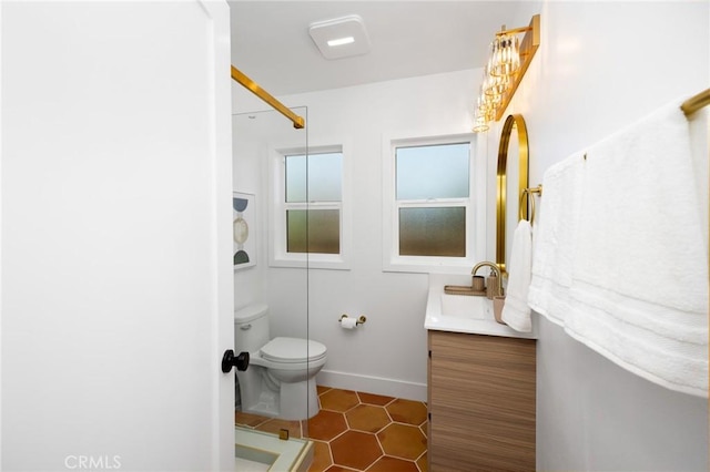 bathroom with vanity, toilet, a shower, tile patterned floors, and baseboards