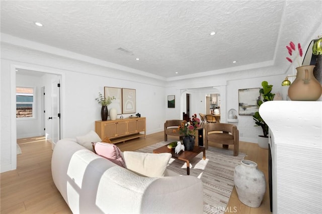 living room featuring recessed lighting, light wood-style floors, a textured ceiling, and baseboards