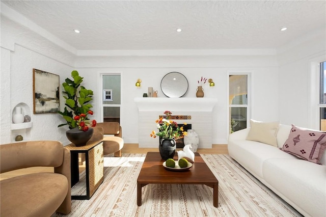 living room featuring a textured ceiling, recessed lighting, wood finished floors, and a lit fireplace